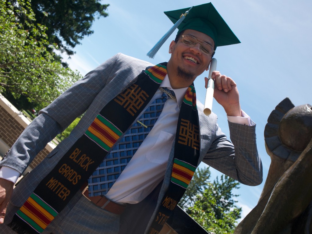 Graduate portrait with diploma under bright sky